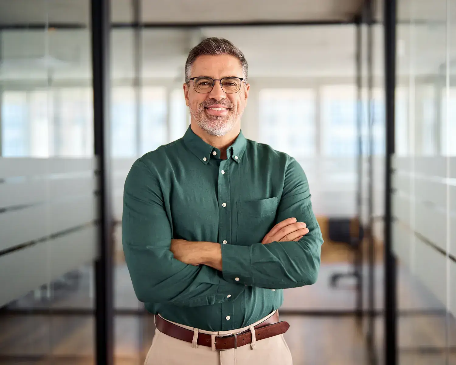 Small business owner standing with arms crossed in an office